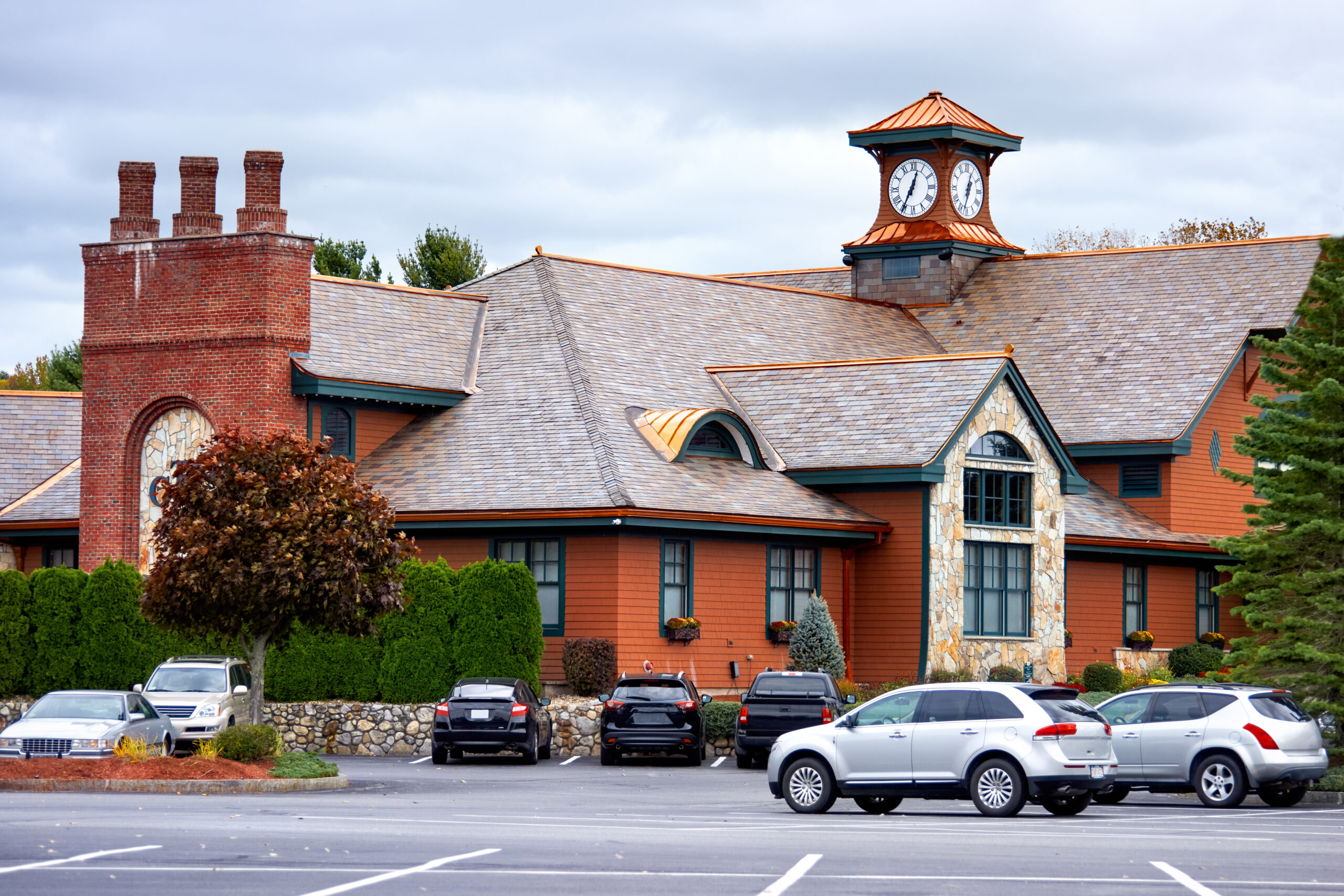 The clubhouse at Tewksbury Country Club with plants and parked cars in front of it, USA